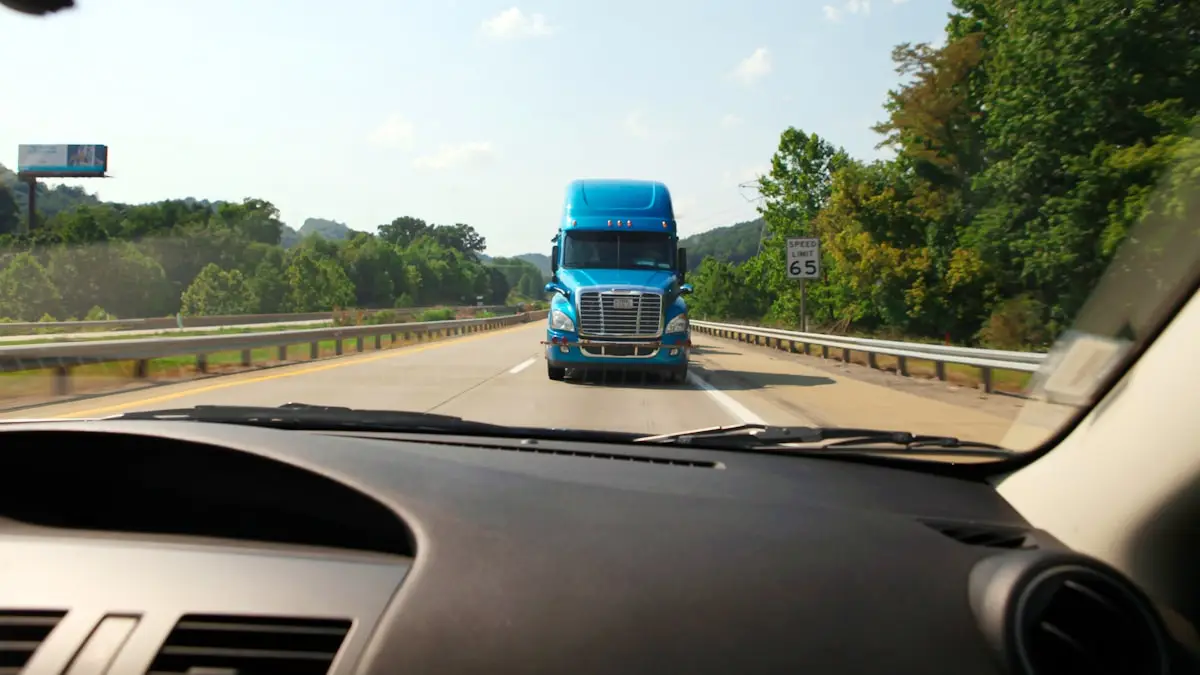 Dashboard view through a windshield of a blue semi truck ahead on the highway