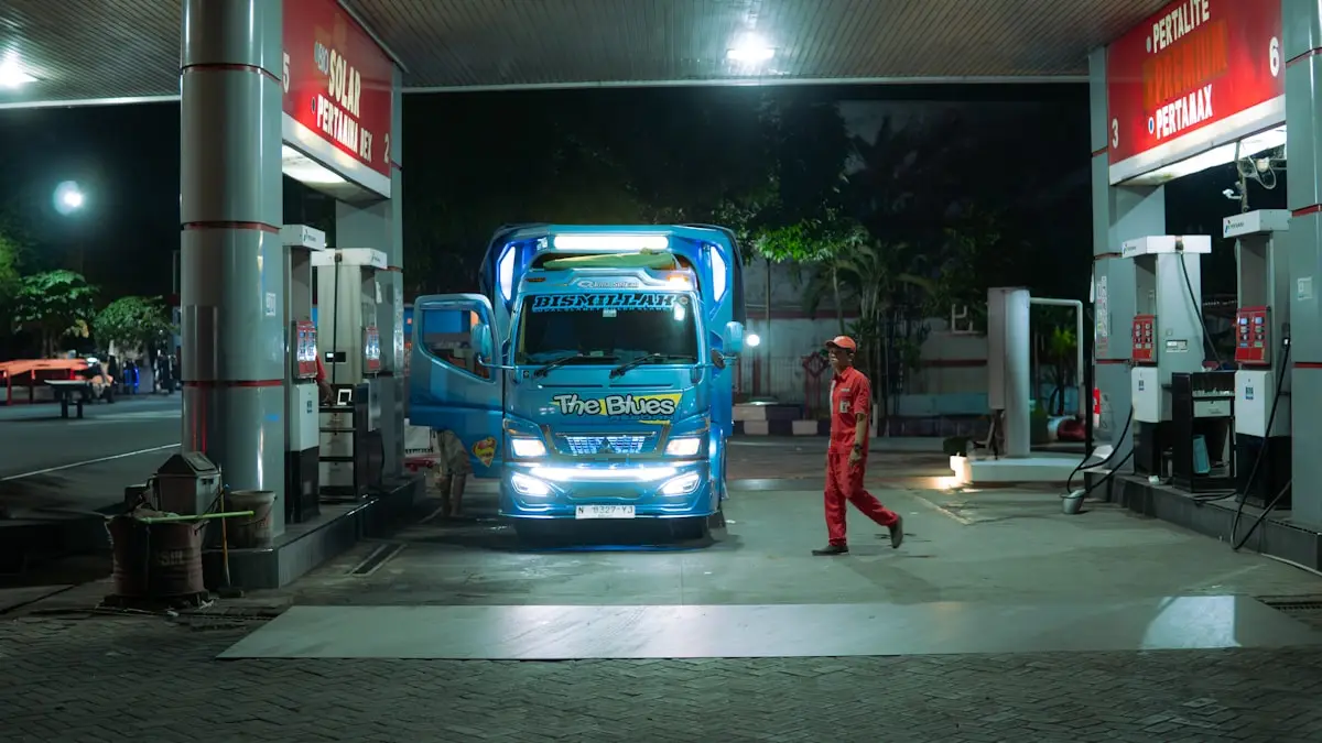 A driver in a work uniform walking toward a parked blue truck