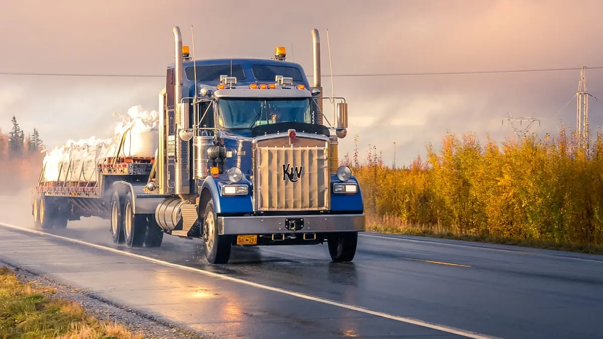 A white and blue truck on the road on a clear day